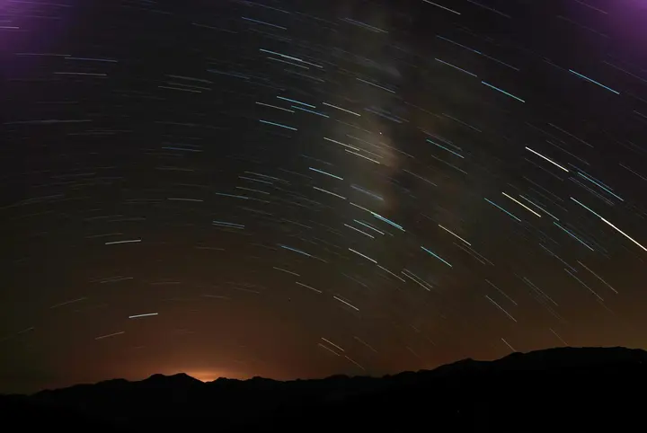 黯黑天空上有段段星軌（星體移動的痕跡），為一張長時間曝光製作的天文圖像